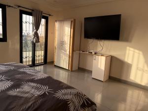 a bedroom with a flat screen tv on the wall at Studio avec Jacuzzi Aeroport AIBD in Déni Diarke
