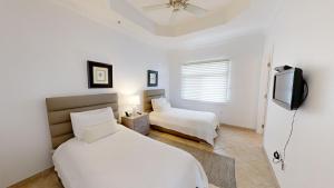 ein Schlafzimmer mit zwei Betten und einem Flachbildfernseher in der Unterkunft South Bay Beach Club #37 Penthouse - 3 Bedroom 3 Bathroom Unit in George Town