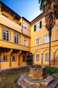 Un edificio amarillo con una palmera delante. en Busdraghi Luxury Apartment, en Lucca