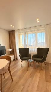 a living room with two chairs and a table at Park Apartments in Mažeikiai