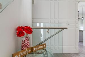 a glass staircase with red flowers in a vase at Brand New, Cheerful, Exquisite 4 BR house, fast wifi, free parking in Langley
