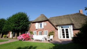 a thatched house with a table and chairs in the yard at Friesenhof Feer in Oldsum
