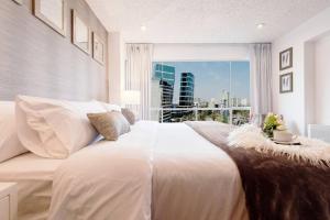 une chambre avec un grand lit blanc avec une grande fenêtre dans l'établissement OceanFront Larcomar Apartments, à Lima