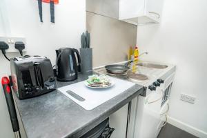 a small kitchen with a stove and a plate of food at Compact & Cosy Central Coventry Budget Studio in Coventry