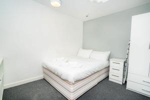 a white bedroom with a bed and a dresser at Compact & Cosy Central Coventry Budget Studio in Coventry