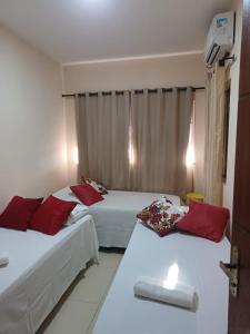 a hotel room with two beds with red pillows at Paraíso de Santa Cruz in Santa Cruz Cabrália