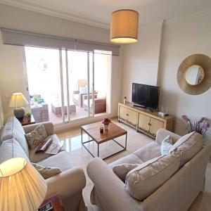 ein Wohnzimmer mit zwei Sofas und einem Fernseher in der Unterkunft Apartamento amplio, cómodo y familiar en Duquesa Hills in Manilva