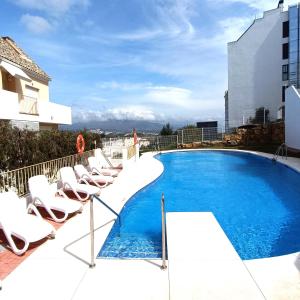 ein Pool auf dem Dach eines Gebäudes mit Liegestühlen in der Unterkunft Apartamento amplio, cómodo y familiar en Duquesa Hills in Manilva