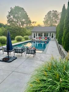 Una piscina con sillas y una sombrilla al lado de una casa. en The Farm at Fox Hollow, en Middletown