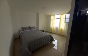 um pequeno quarto com uma cama e uma janela em Hotel El Redil em Ipiales