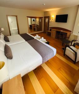 a hotel room with a large bed and a living room at Real Ferrol in Ferrol