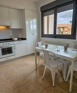 a white kitchen with a white table and chairs at Casa Entre Viñas, jardin privado con piscina comunitaria in Uruñuela