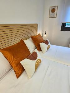 two white beds with brown and white pillows on them at Casa Entre Viñas, jardin privado con piscina comunitaria in Uruñuela