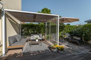 a patio with a couch and an umbrella on a deck at Apartments Casa Emonia in Novigrad Istria