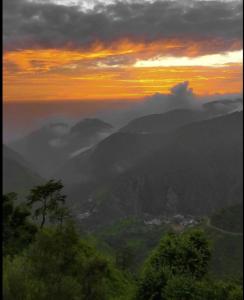 a view of a valley with clouds in the sky at The Village Lodge Dalhousie in Banikhet +2 photos