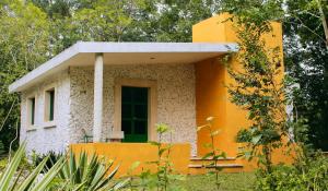 a small yellow and white house with a porch at El Prado- Rancho familiar en Yucatán in Xocchel