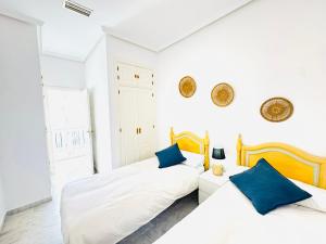 two beds in a white room with blue pillows at La Casita Gaditana in Cádiz