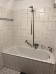 a white bath tub in a white tiled bathroom at Apartment near trade fair, rhine and city in Cologne +4 photos