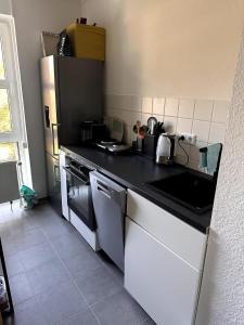 a kitchen with a black counter top and a refrigerator at Apartment near trade fair, rhine and city in Cologne