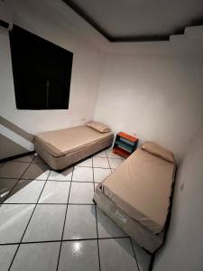 a room with two beds and a tv on the wall at O Portal hospedaria in Paraty
