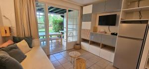 ein Wohnzimmer mit Couch und Fernseher und eine Küche in der Unterkunft Appartement cosy sous pinède lac de Biscarrosse rénové in Biscarrosse