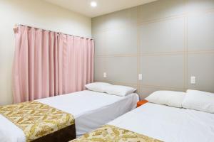 two beds in a room with pink curtains at Y's INN NishiShinjuku 018T in Tokyo