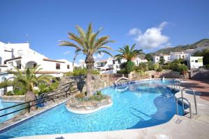 a large swimming pool with palm trees and houses at CAPISTRANO BREEZE - Luxury Coastal Apartment in Capistrano Village, Nerja in Nerja