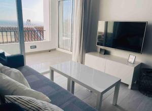 a living room with a couch and a tv and a table at CAPISTRANO BREEZE - Luxury Coastal Apartment in Capistrano Village, Nerja in Nerja