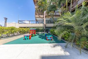 a playground in front of a building with palm trees at Barra Bali - Pé na Areia, Vista Mar Incrível - Destino BSM 116 in Barra de São Miguel