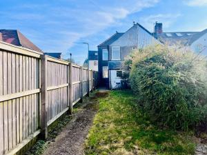 a fence next to a house with a bush at Charming End of Terrace Home with Garden in Cardiff