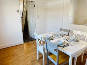 a white dining room with a white table and chairs at Charming End of Terrace Home with Garden in Cardiff