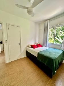 a bedroom with a bed with red pillows and a window at Apartamento Bela Vista Porto Real Resort in Mangaratiba