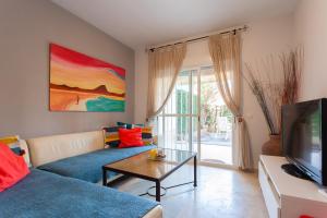 a living room with a blue couch and a tv at Divi Apartments Costa Ballena in Costa Ballena