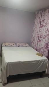 ein Bett in einem Zimmer mit einer weißen Wand in der Unterkunft Casa com 2 quartos e 2 banheiros na Lagoa do Centro in São Pedro da Aldeia