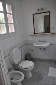 a white bathroom with a toilet and a sink at Hotel El Molino in Venado Tuerto