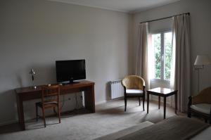 a living room with a desk with a television and chairs at Hotel El Molino in Venado Tuerto