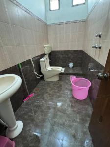 a bathroom with a toilet and a pink bucket at AWARI in Guest House in Hyderabad +10 photos