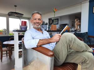 a man sitting in a chair reading a book at 360 degrés sur la rochelle chambre d hôte in La Rochelle