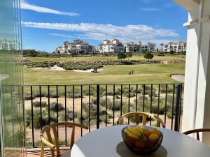 a balcony with a table and chairs and a golf course at Stunning frontline apartment with golf views and pool in Sucina