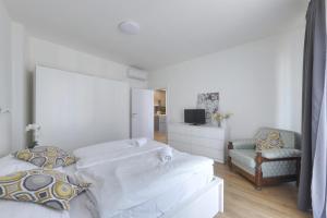 a white bedroom with two beds and a chair at Shon apartment Old Town in Bratislava