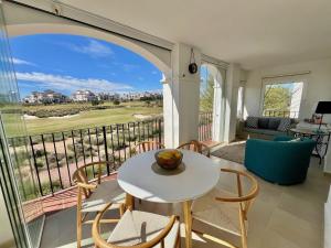 a living room with a table and chairs on a balcony at Stunning frontline apartment with golf views and pool in Sucina +21 photos