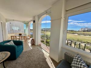 a living room with a couch and a large window at Stunning frontline apartment with golf views and pool in Sucina