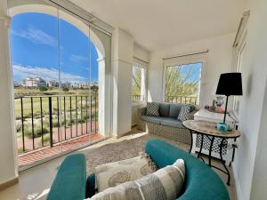 a living room with a couch and a table at Stunning frontline apartment with golf views and pool in Sucina