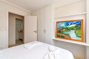 a white bedroom with a painting on the wall at Bem Proximo a Catedral - stayhousetemporada in Canela