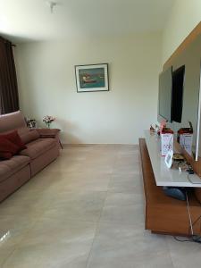 a living room with a couch and a flat screen tv at Aconchego in São Pedro da Aldeia