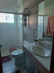 a bathroom with a sink and a toilet and a mirror at Aconchego in São Pedro da Aldeia