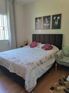 a bedroom with a large bed and a chair at Aconchego in São Pedro da Aldeia