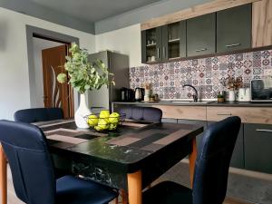 cocina con mesa negra y sillas azules en Madalina's House, en Brasov
