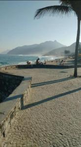 リオデジャネイロにあるSuíte e Quarto em apto Compartilhado Frente Marのヤシの木と海の砂浜 +4枚の写真