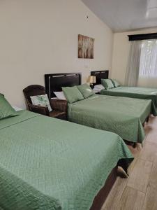 a hotel room with three beds with green blankets at Villa JR 4 near the Guacalillo Rock in Tivives